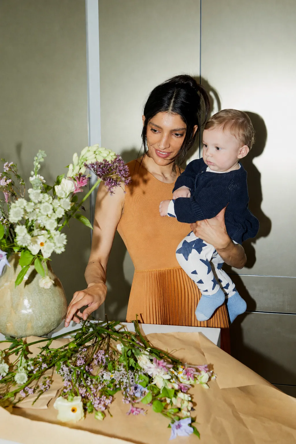 An Atelier 23 creator arranging flowers while holding her child