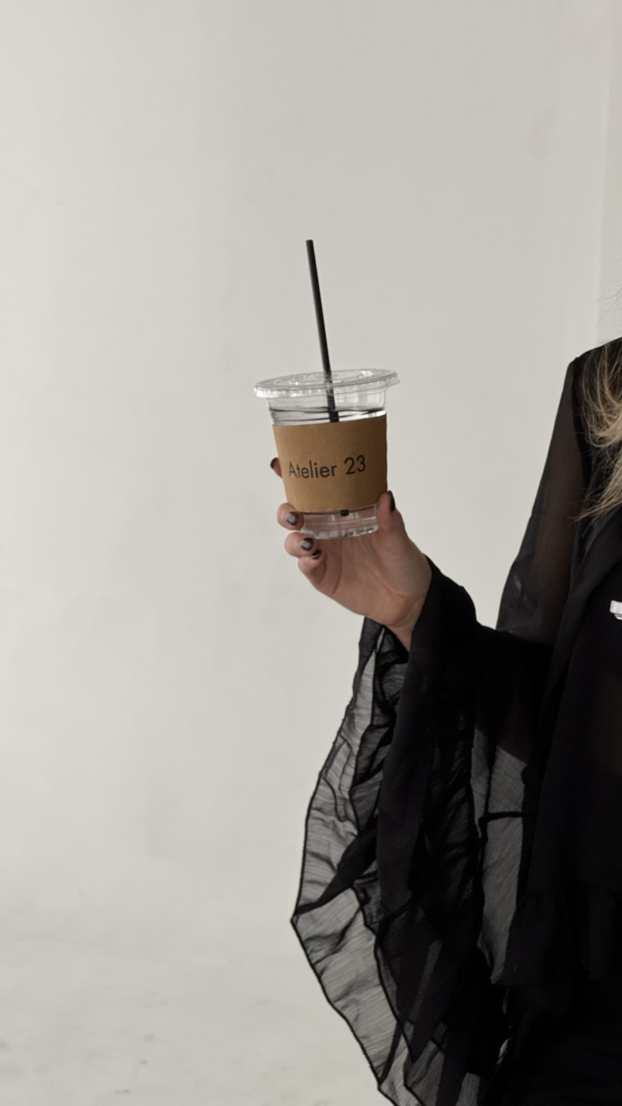 A hand holding an Atelier 23 branded drink